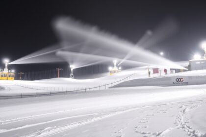 Hóágyúzás a sípályán éjszaka, havas táj és világító berendezések.