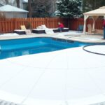 Két ember medence téliesítése, fehér takaróval.