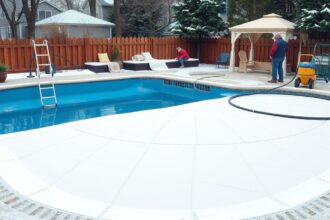 Két ember medence téliesítése, fehér takaróval.