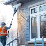 Téli ablakok tisztítása egy férfi által, hóval borított háttérben.