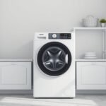 Modern mosógép otthon, fehér fal és bútorok között.